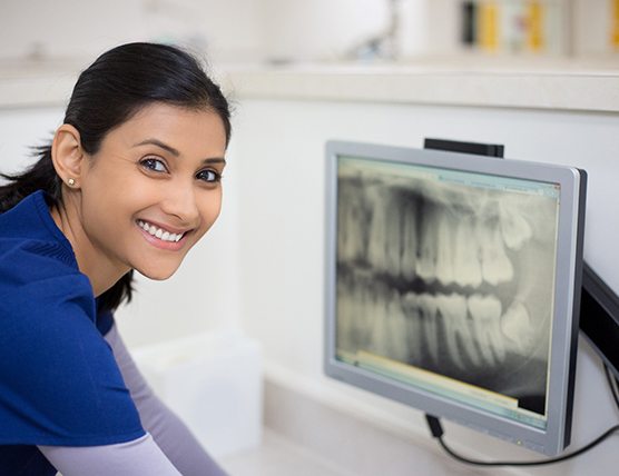 dental assistant smiling while looking at X-ray 